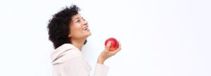 Side portrait of happy asian woman holding apple against white background